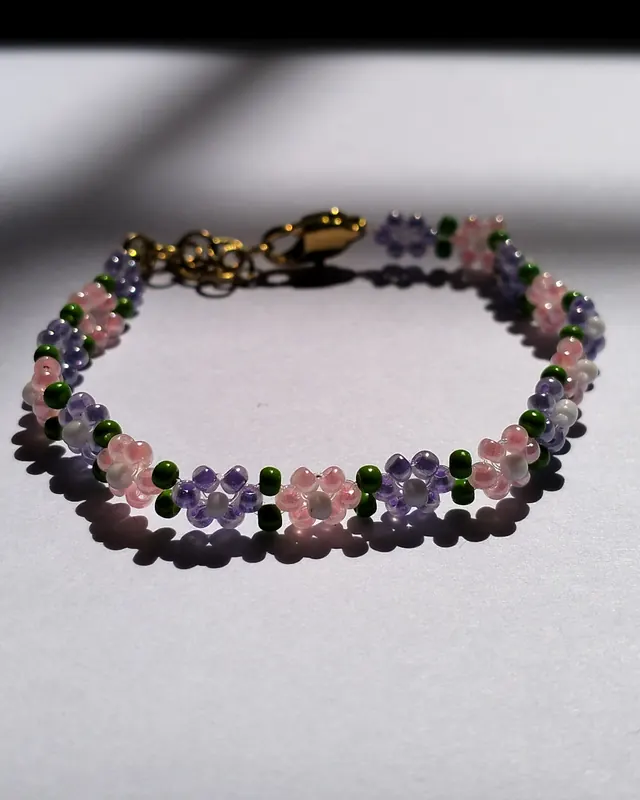 A violet, pink and green flower chain bracelet in sunlight