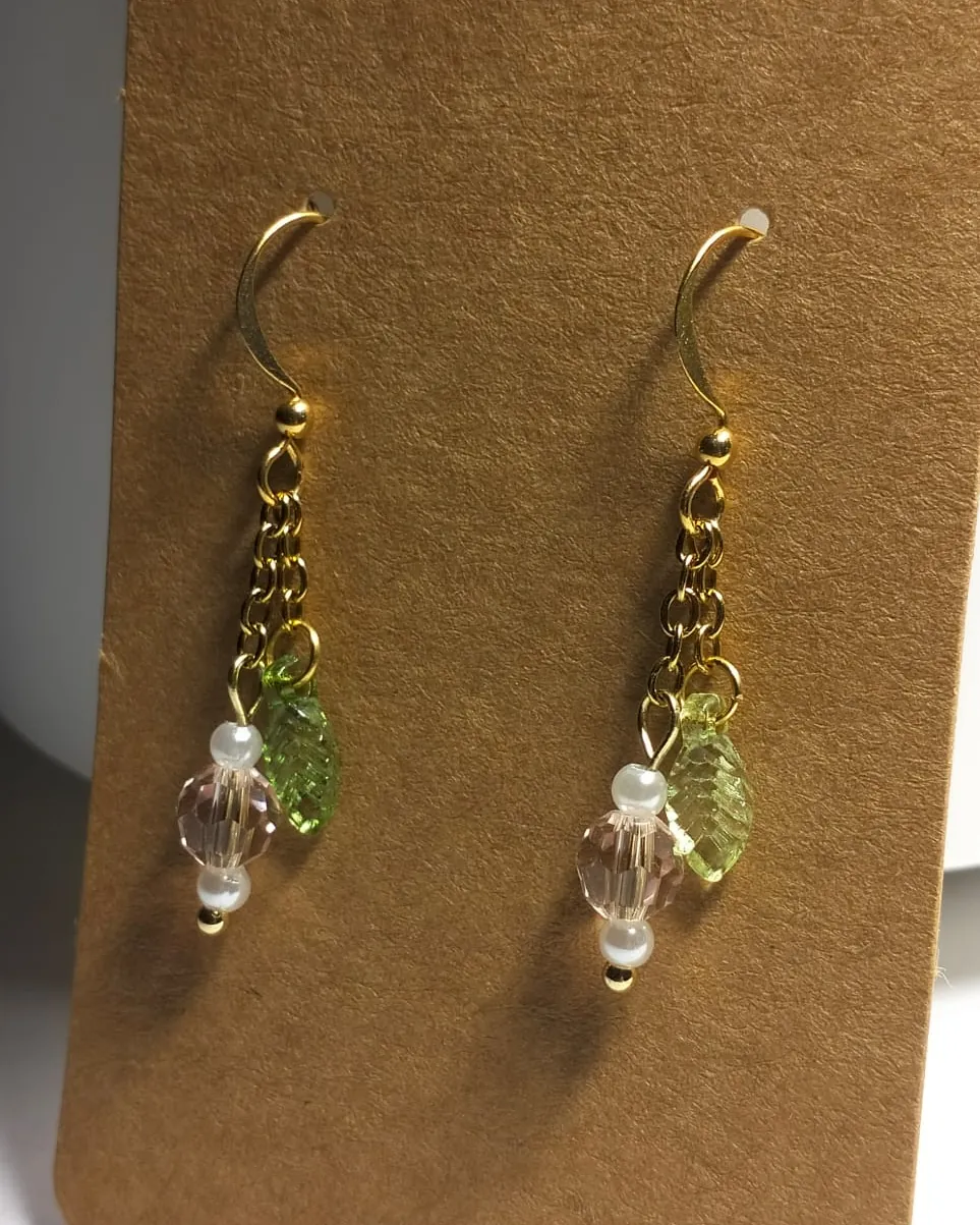 Gold tone drop earrings with clear glass and green glass leaves, on a kraft card