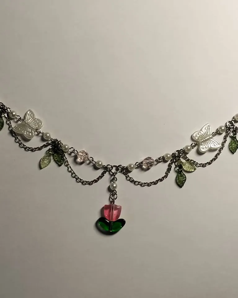 A layered steel chain necklace with clear glass flowers, green leaves and a tulip charm